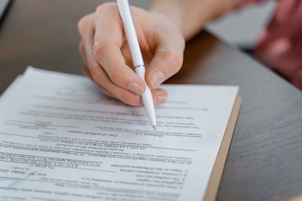 Main signant un document avec un stylo