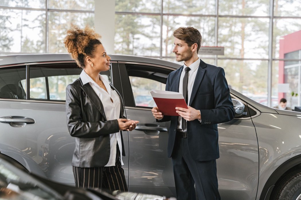 Cliente discutant d’un achat de voiture avec un vendeur