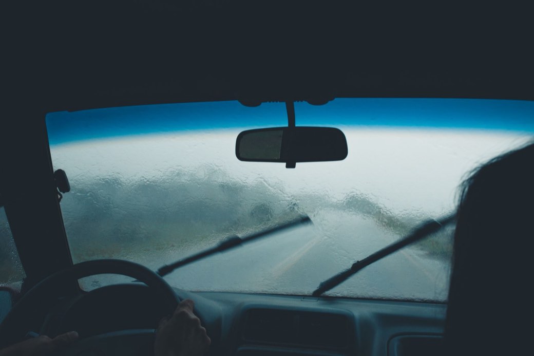 Pare-brise couvert de gouttes de pluie vu depuis l’habitacle