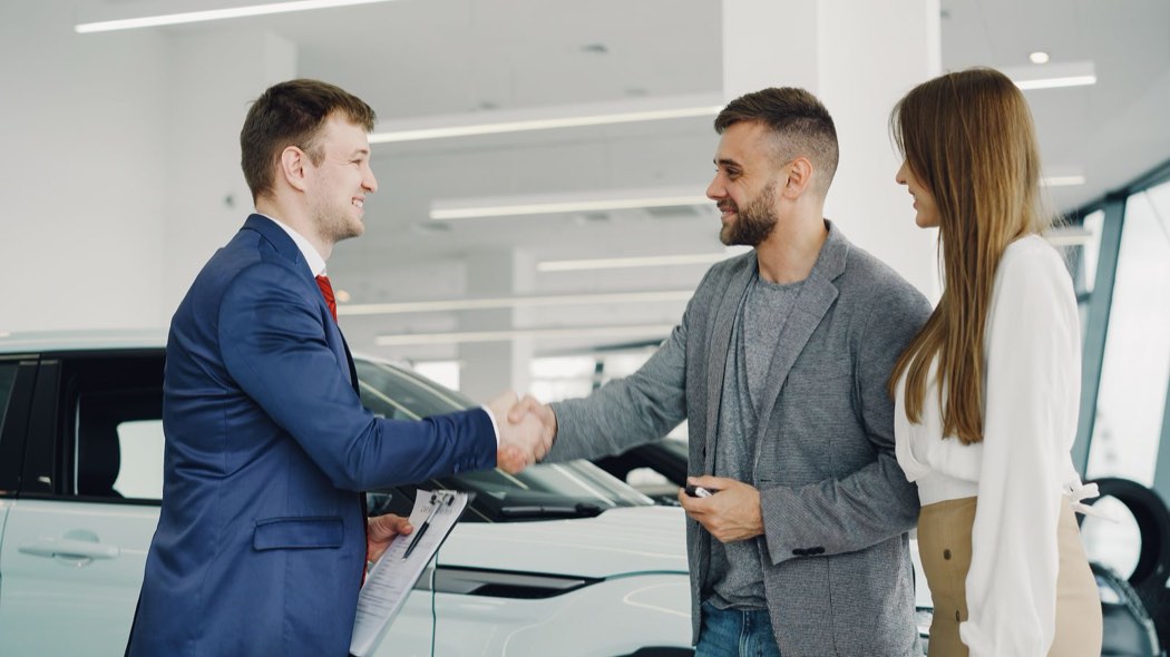 Poignée de main entre un vendeur automobile et des clients