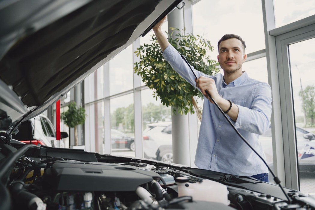 Personne inspectant le moteur d’une voiture avant achat