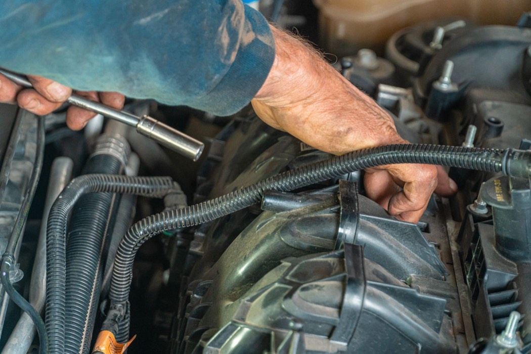 Mécanicien intervenant sur un moteur de voiture en atelier