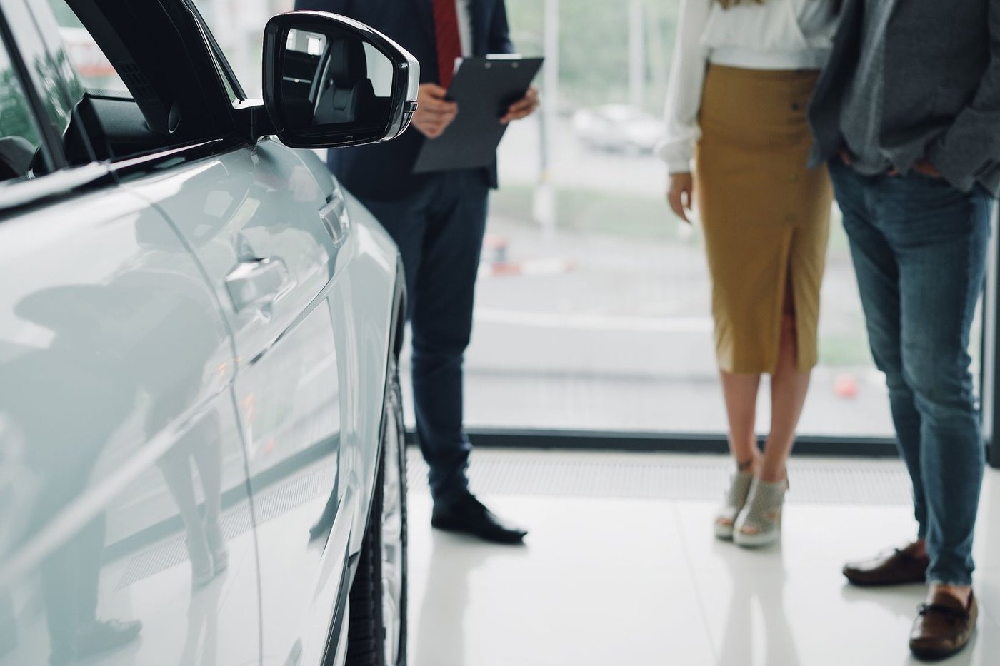 Clients et vendeur autour d'une voiture en concession