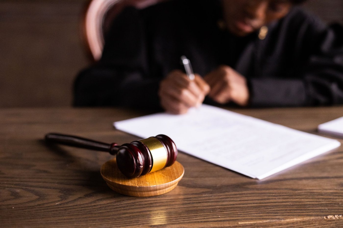 Magistrat signant des documents à son bureau, marteau d’audience au premier plan