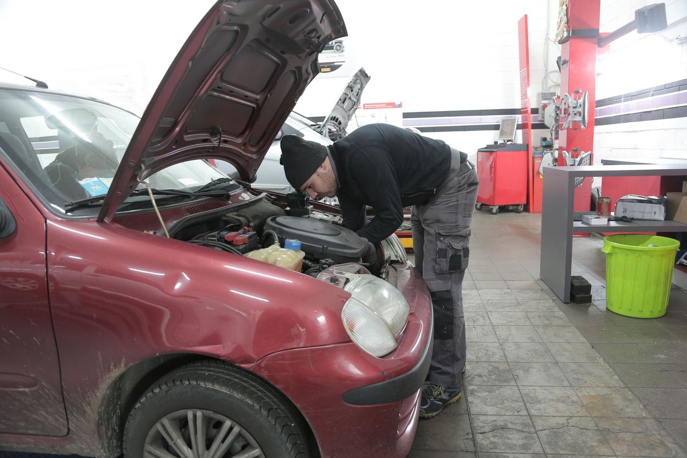 Mecanicien penche sur le moteur d'une citadine