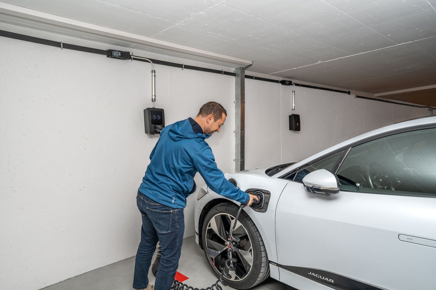 Branchement d'une voiture électrique à une borne murale dans un parking