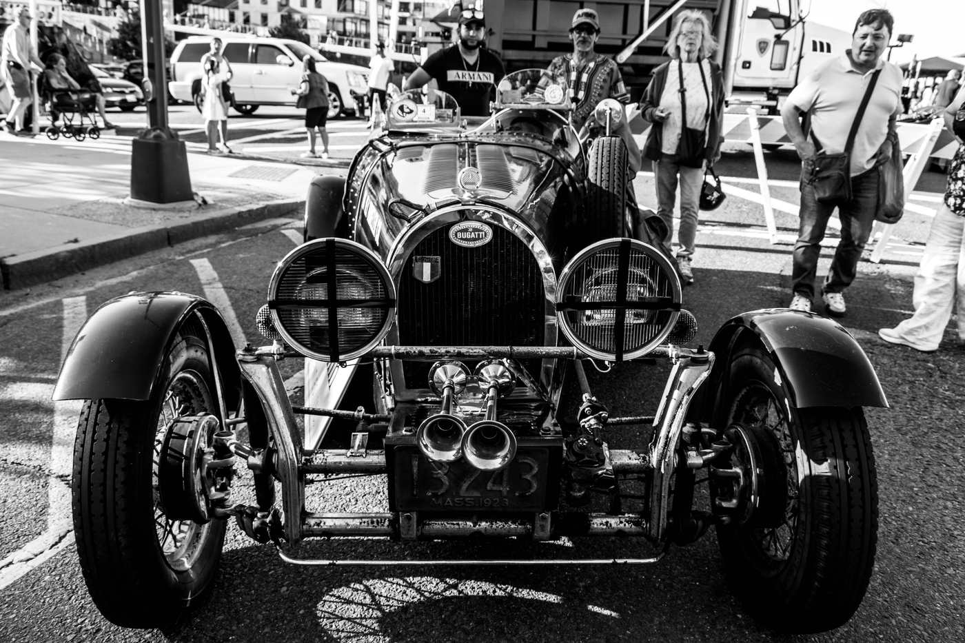 Bugatti Type 35 en noir et blanc entourée de spectateurs lors d'un rassemblement