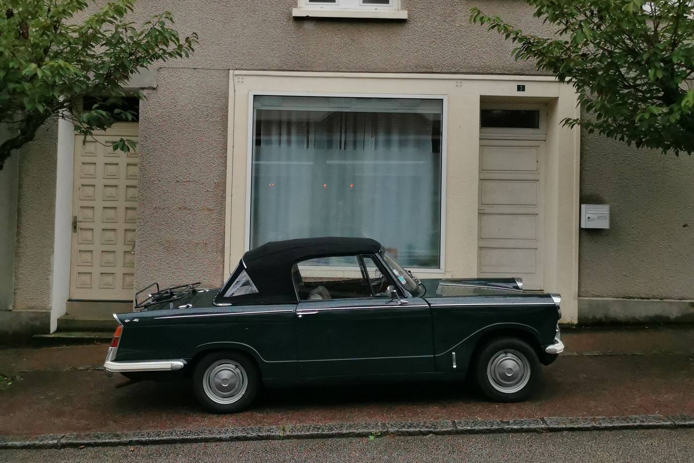 Petit cabriolet ancien garé devant une maison