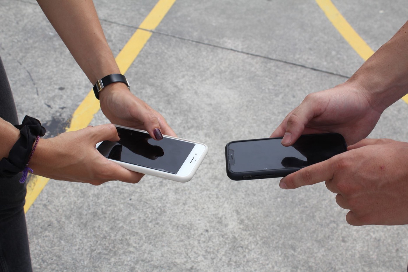 Deux personnes tenant chacune un smartphone sur une chaussée marquée
