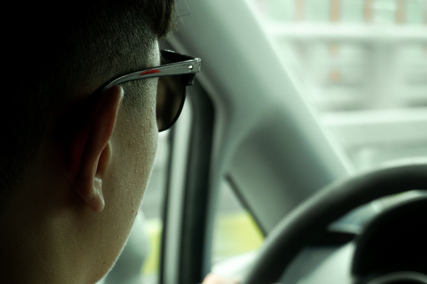 Jeune conducteur vu de dos, mains sur le volant en ville