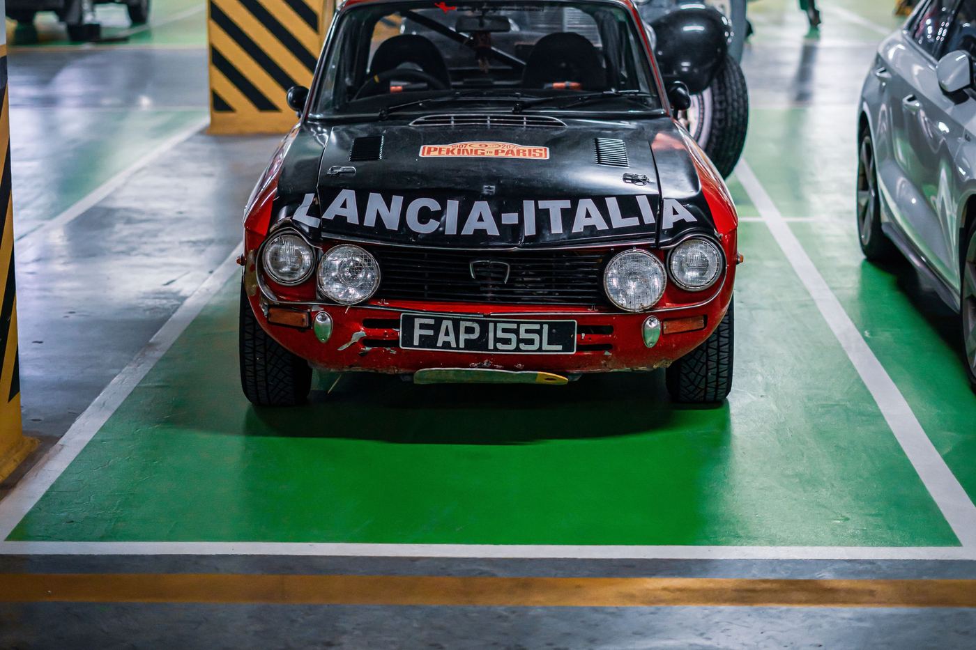 Lancia Fulvia Coupé HF en configuration rallye dans un parking