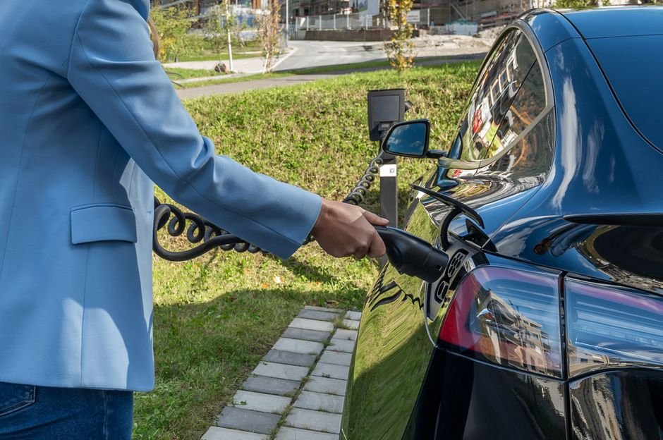 Personne branchant une voiture électrique sur une borne de recharge