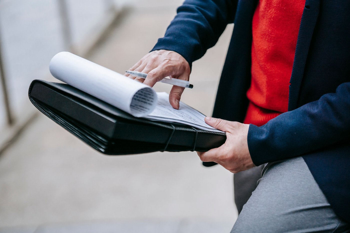 Mains parcourant un dossier de documents avec un stylo