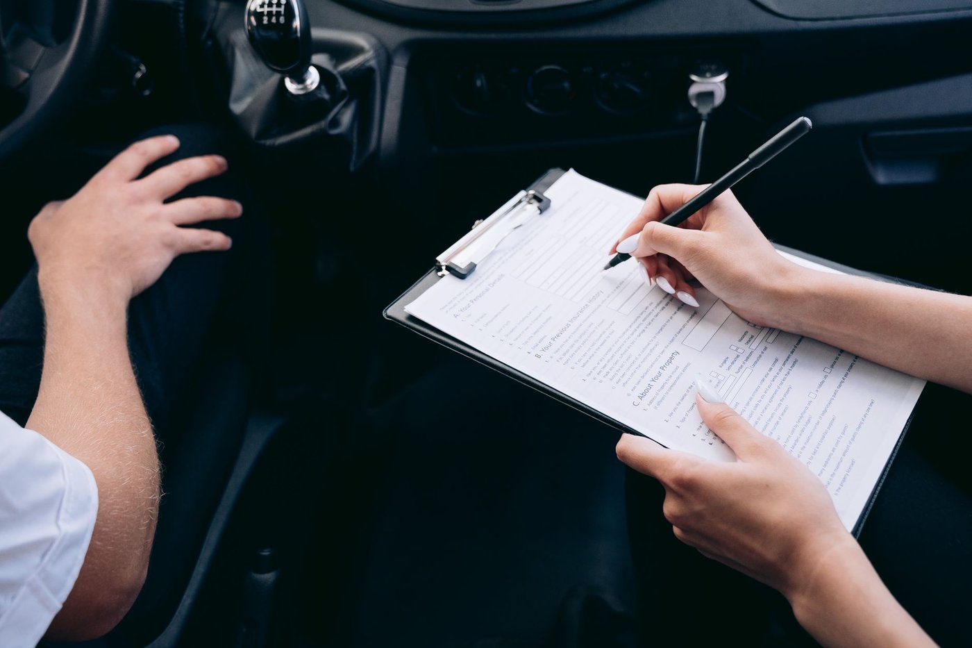 Deux personnes remplissant un formulaire sur porte-bloc dans une voiture