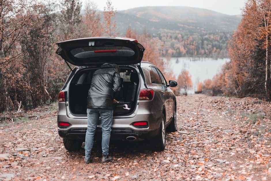 Homme chargeant le coffre d'un grand SUV familial en pleine nature