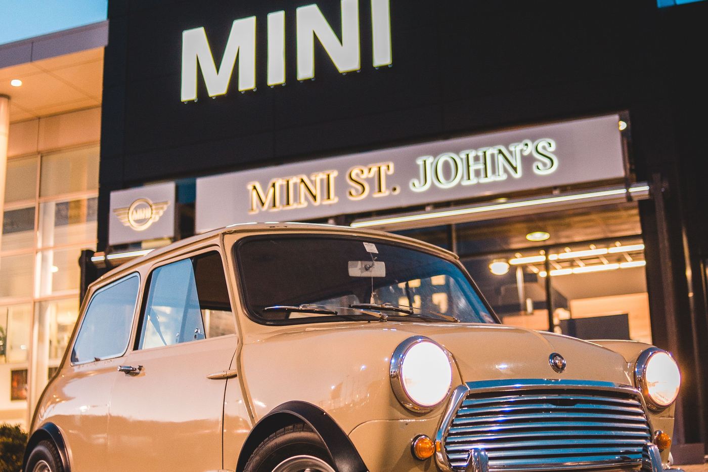 Mini classique garée devant une concession MINI moderne