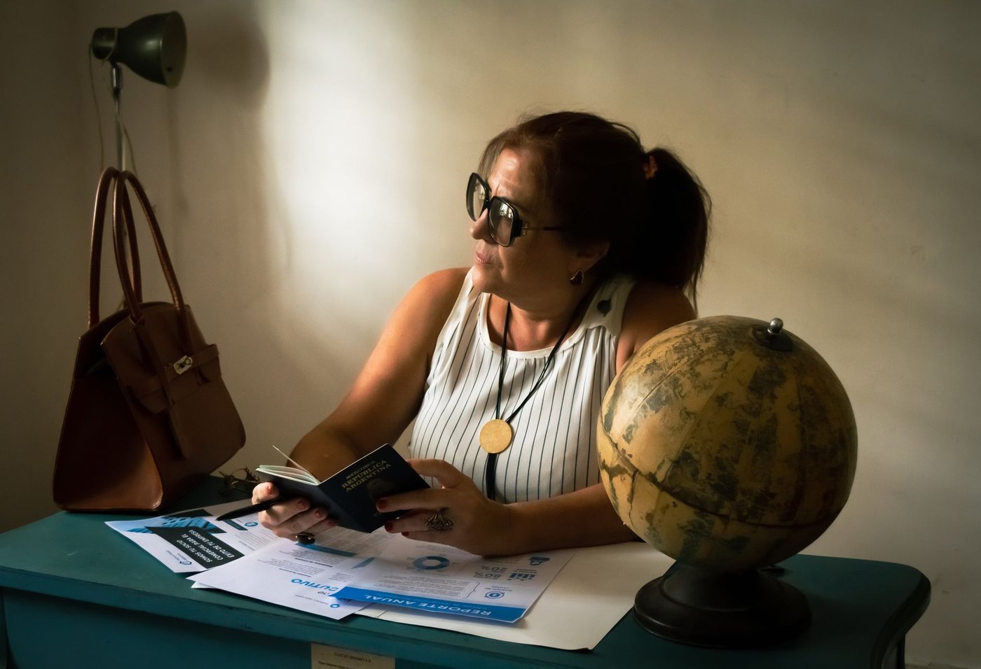 Personne examinant des documents de voyage à côté d’un globe terrestre