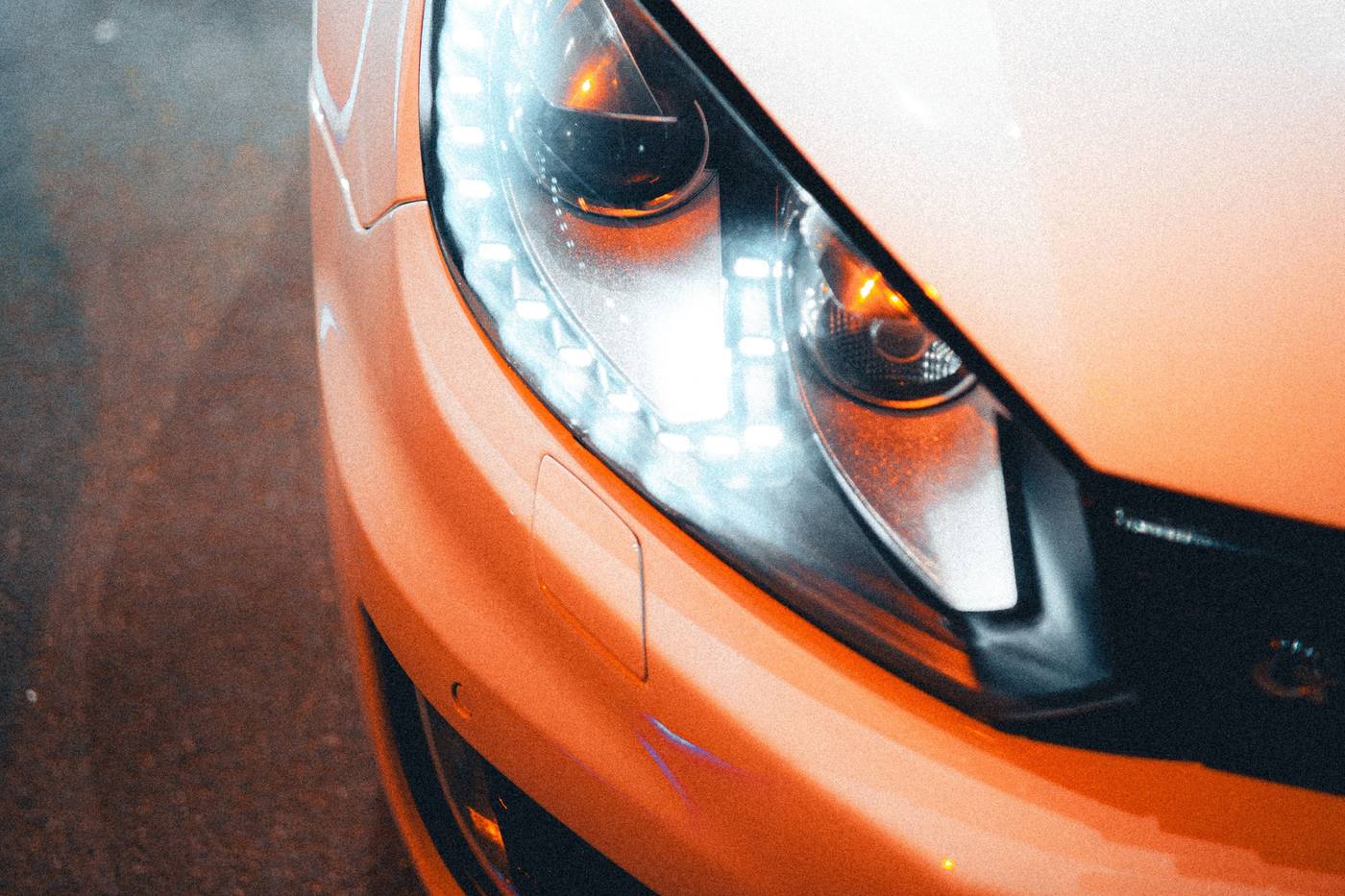 Phare avant allumé de nuit sur une voiture orange