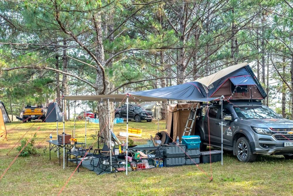 Campement avec tente de toit et auvent déployé sur un pick-up