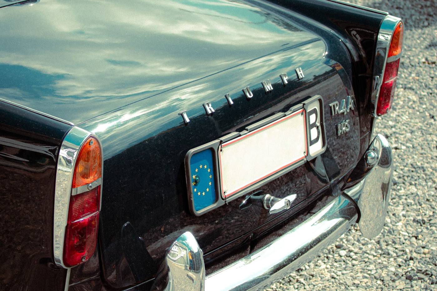 Arrière d'une Triumph TR4A noire, la devancière dessinée par Michelotti