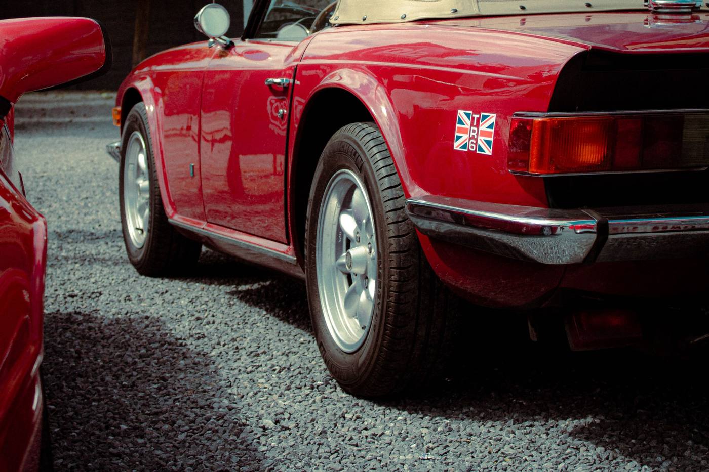Triumph TR6 rouge vue de trois quarts arrière avec son toit rigide
