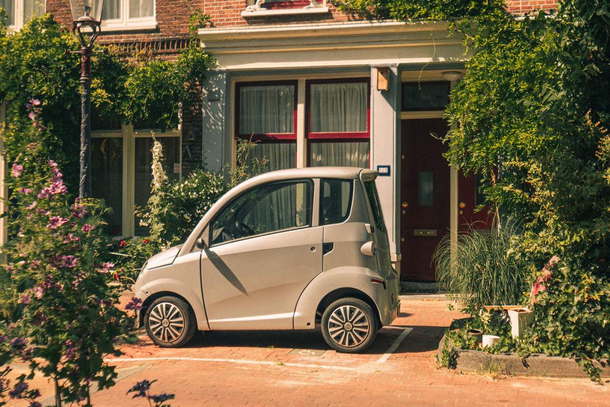 Voiture sans permis grise garée devant une maison en ville