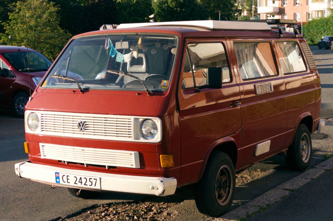 Volkswagen T3 Caravelle rouge et blanc garé dans une rue, avec sa galerie de toit
