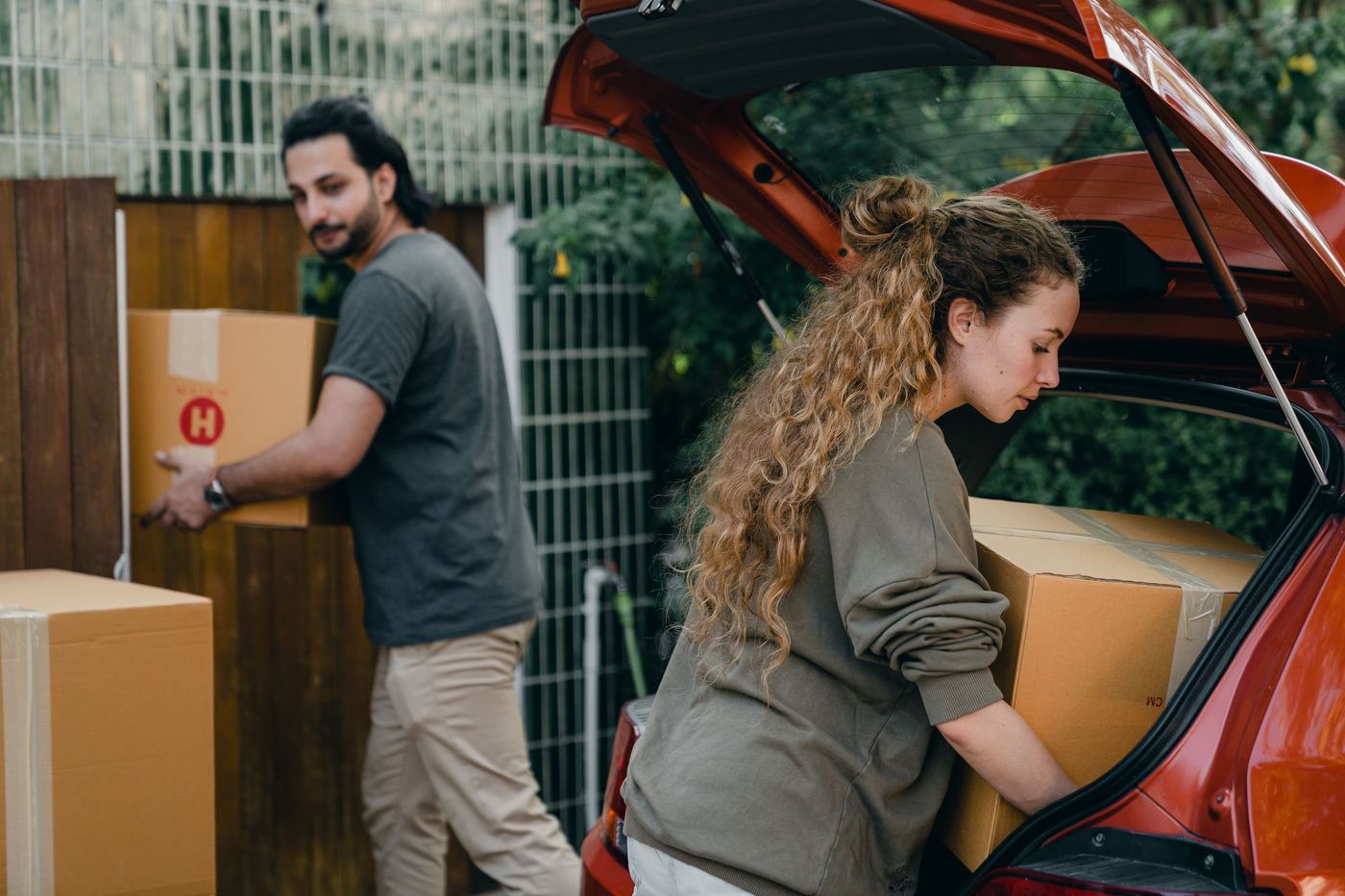 Couple déchargeant des cartons du coffre d'une voiture lors d'un déménagement