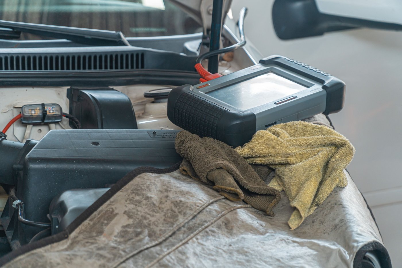 Tablette de diagnostic posée sur l'aile d'une voiture, capot ouvert